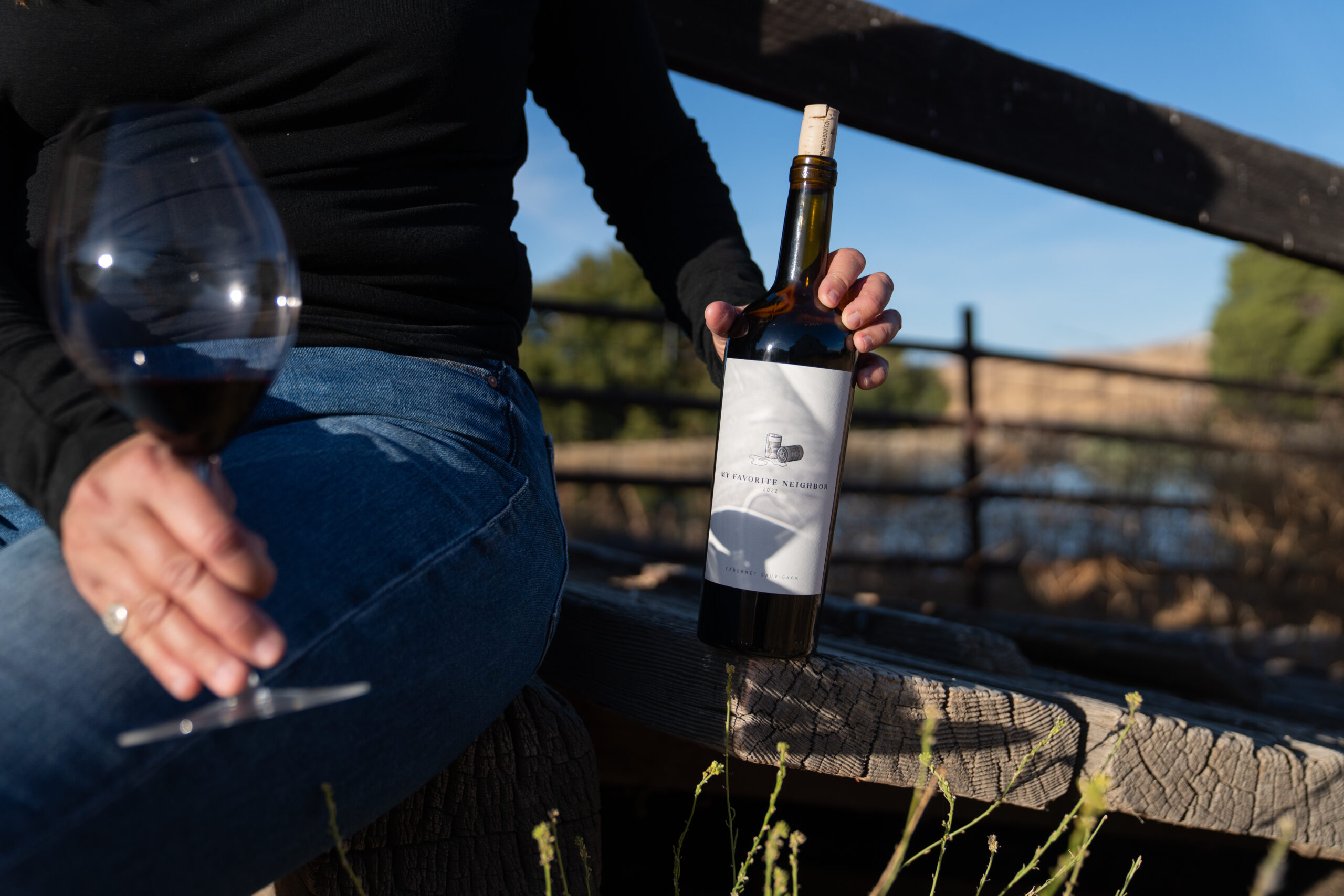 a person holding a bottle and glass of wine